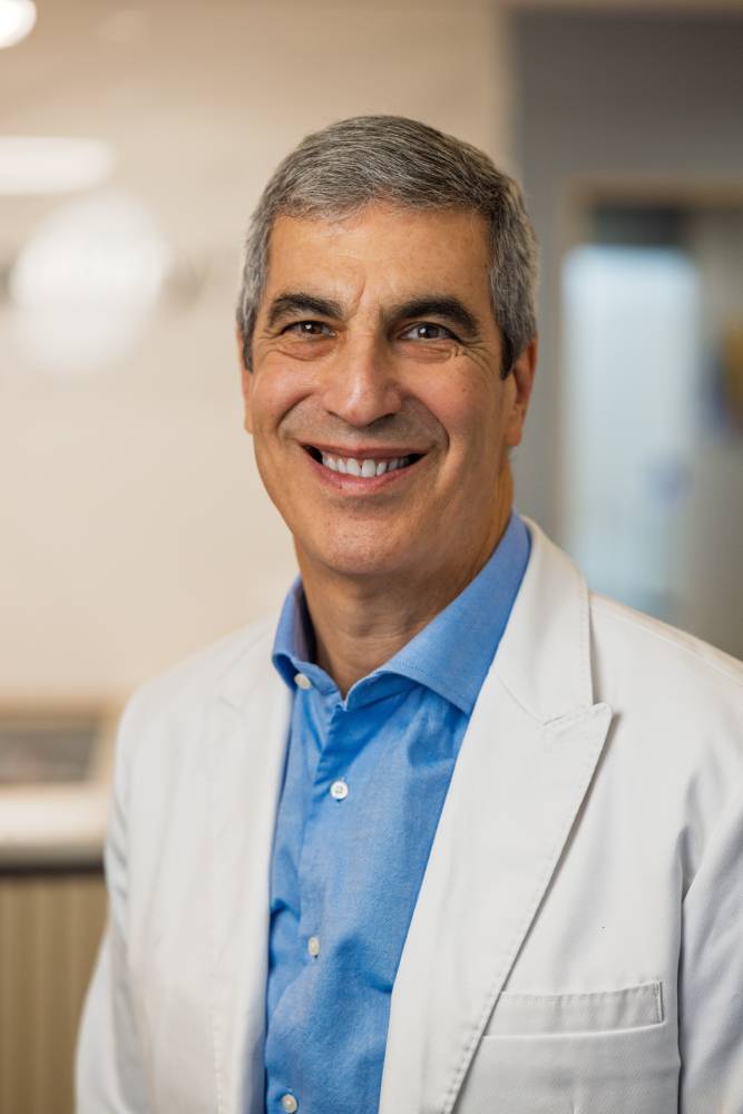 Portrait of Dr. Andrew Koenigsberg smiling in a white coat with his name displayed below on a dental website profile – Andrew Koenigsberg