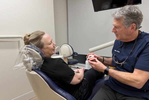 A dentist showing a patient a dental oral appliance used as a natural treatment option for sleep apnea in a dental office – sleep apnea natural treatment midtown nyc