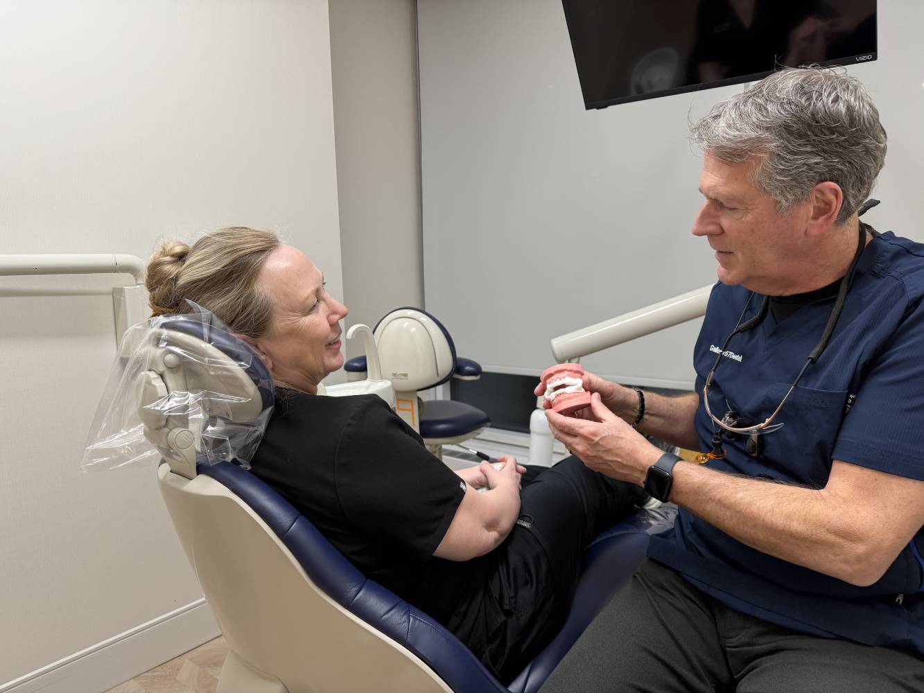 A dentist showing a patient a dental oral appliance used as a natural treatment option for sleep apnea in a dental office – sleep apnea natural treatment midtown nyc