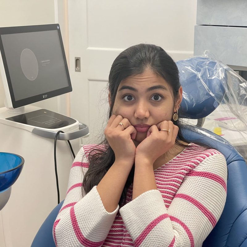 A patient sitting in a dental chair with a concerned expression while waiting for a dental checkup, representing common causes of dental decay – causes of dental decay