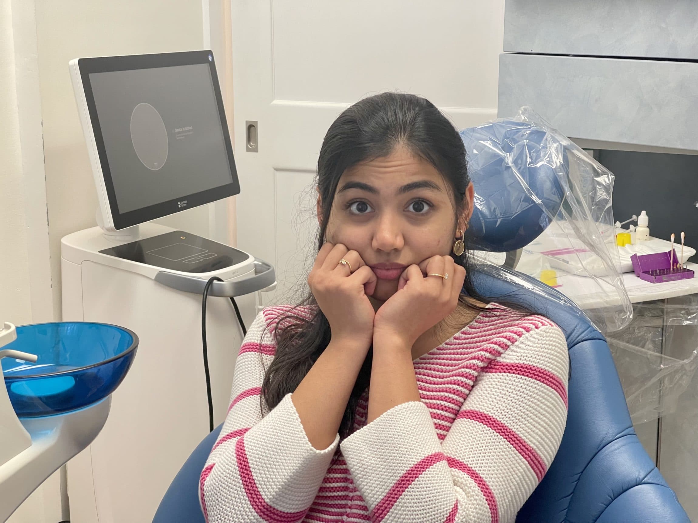 A patient sitting in a dental chair with a concerned expression while waiting for a dental checkup, representing common causes of dental decay – causes of dental decay